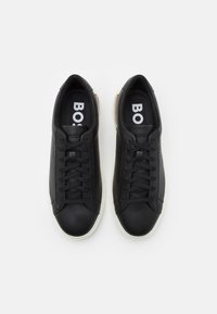 Svarta lädersneakers med en slät yta, med snörningsdesign och vita gummisulor. Inuti syns en logotyp på innersulorna.