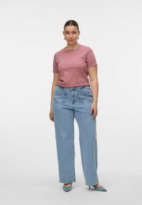 Camiseta de manga corta rosa combinada con unos vaqueros de pierna ancha de cintura alta en azul claro. Presenta líneas limpias y un corte relajado.