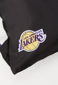 Sac en nylon noir avec un logo des Los Angeles Lakers en jaune et violet, présentant un design de basketball et une broderie.