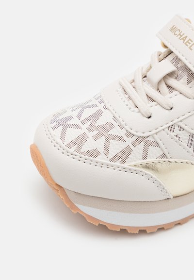 Lichtgekleurde sneaker met een gestructureerde bovenkant met geometrische patronen, een gouden accent en een rubberen zool met een gripprofiel.