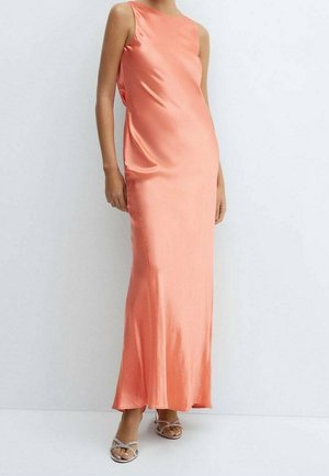 Ärmelloses, bodenlanges Korallensatin-Kleid, getragen mit silbernen Riemchen-Sandaletten mit Absatz vor einem schlichten weißen Hintergrund.