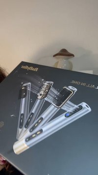 Babyliss stylingverktøykasse med sølvfargede håndtak, ulike børstevedlegg, leopardmønsterdetalj og kontrollknapper mot en mørk bakgrunn.