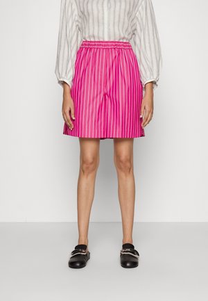 Shorts roses rayés avec une taille élastique, design longueur genou, tissu léger, associés à des chaussures plates noires et un blouse rayée.