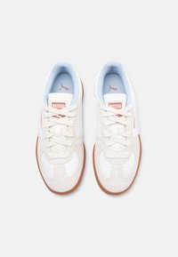 Zapatillas blancas con parte superior sintética suave, forro azul claro y suela de goma beige. Presentan cordones redondos y acentos del logo de PUMA.