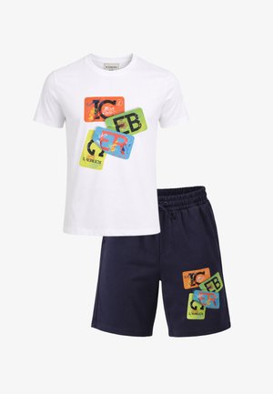 Completo con t-shirt bianca a maniche corte e pantaloncini blu navy, entrambi con stampe grafiche colorate di rettangoli sovrapposti con lettere e scarabocchi.