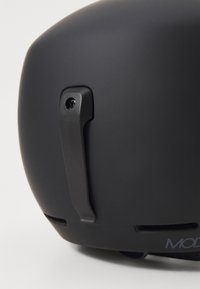 Czarny kask o gładkiej matowej powierzchni, z bocznym zaczepem i otworami wentylacyjnymi, prezentujący prosty, nowoczesny design.