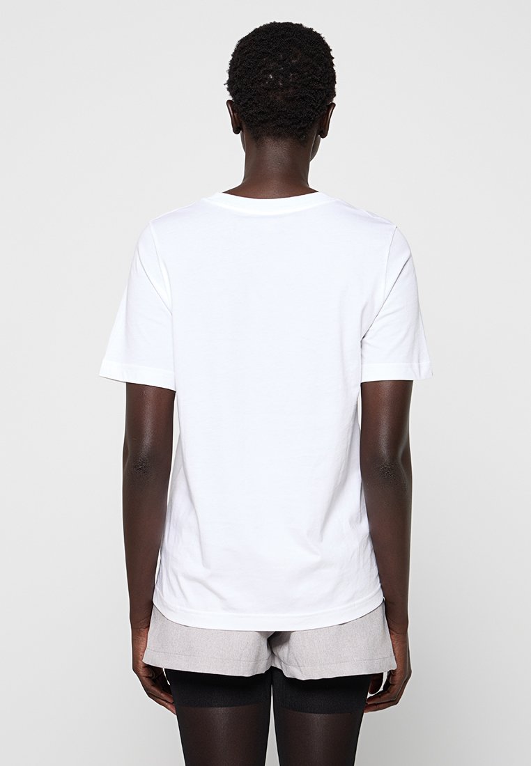 Biała bawełniana koszulka z krótkim rękawem, prostym krojem i okrągłym dekoltem. Materiał wydaje się miękki, z minimalną ilością szwów, bez widocznych wzorów.