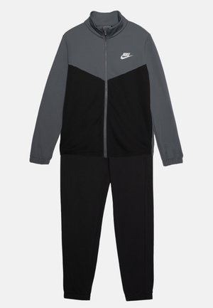 Nike trainingspak in grijs en zwart. Jack met hoge kraag en ritssluiting met een kleurblokontwerp; bijpassende zwarte broek met elastische boorden. Zacht materiaal.