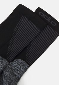 Calcetines en negro y gris que presentan un patrón texturizado, un diseño acanalado y el nombre de la marca tejido en la parte superior. Tela ligera con un ajuste ceñido.
