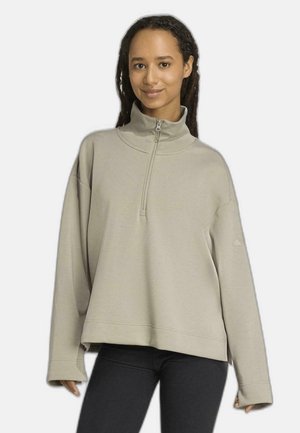 Lichtbeige sweatshirt met een hoge kraag en een kwartrits. Voorzien van een losse pasvorm, verlaagde schouders en een zachte, gladde stoftextuur.