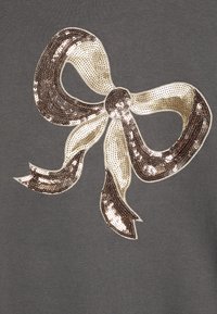 Tissu gris avec un grand nœud en sequins de crème et de bronze, avec des sequins scintillants et une texture lisse, bordé d'une finition subtile.