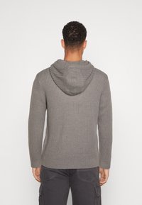 Graue gerippte Strickjacke mit einer ausgeprägten Kapuze, langen Ärmeln und einem taillierten Saum. Einfaches Design mit einer strukturierten Oberfläche.