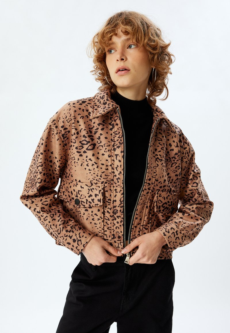 Leopardmönstrad kort jacka i beige och svart, med dragkedja fram, krage och två bröstfickor med svarta knappar. Mjuk textur.