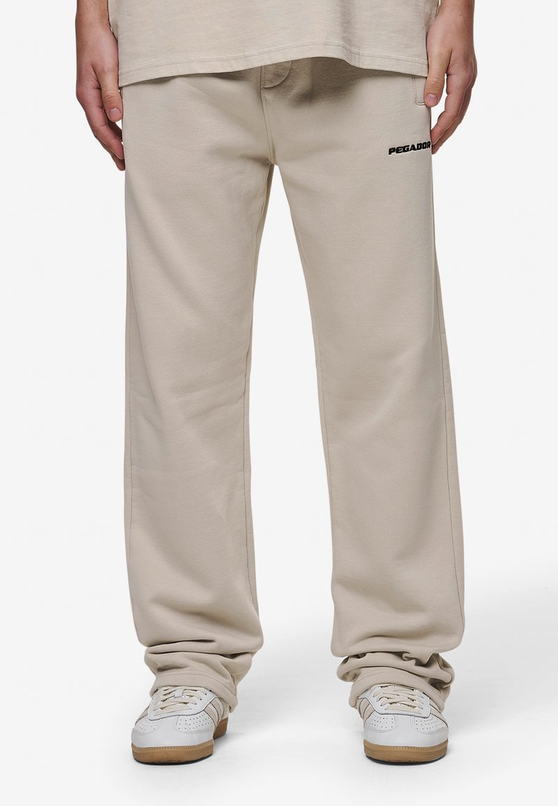 Pantalons de survêtement beiges avec une coupe décontractée, en tissu doux en mélange de coton, avec un petit logo noir 'PEGADOR' sur la cuisse gauche.