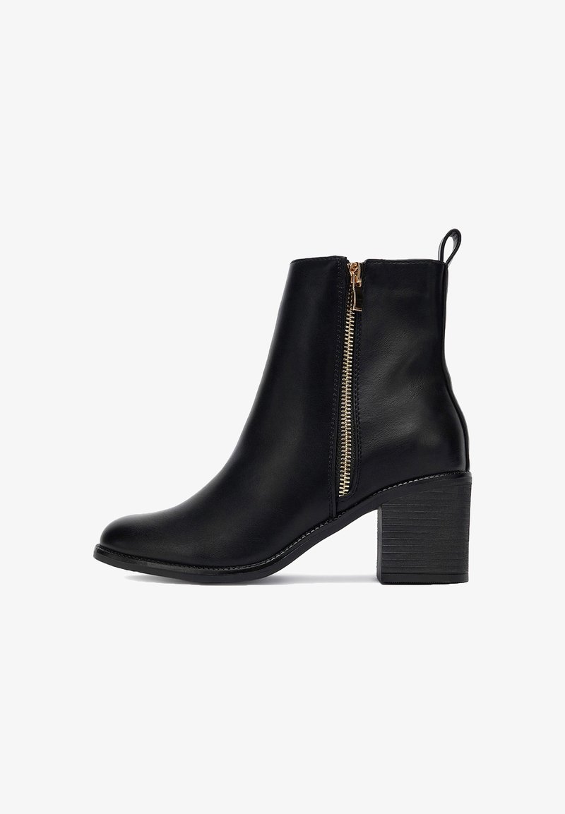 Botín negro de cuero hasta el tobillo con un cierre dorado lateral, tacón cuadrado, punta redonda y tirador en la parte posterior.