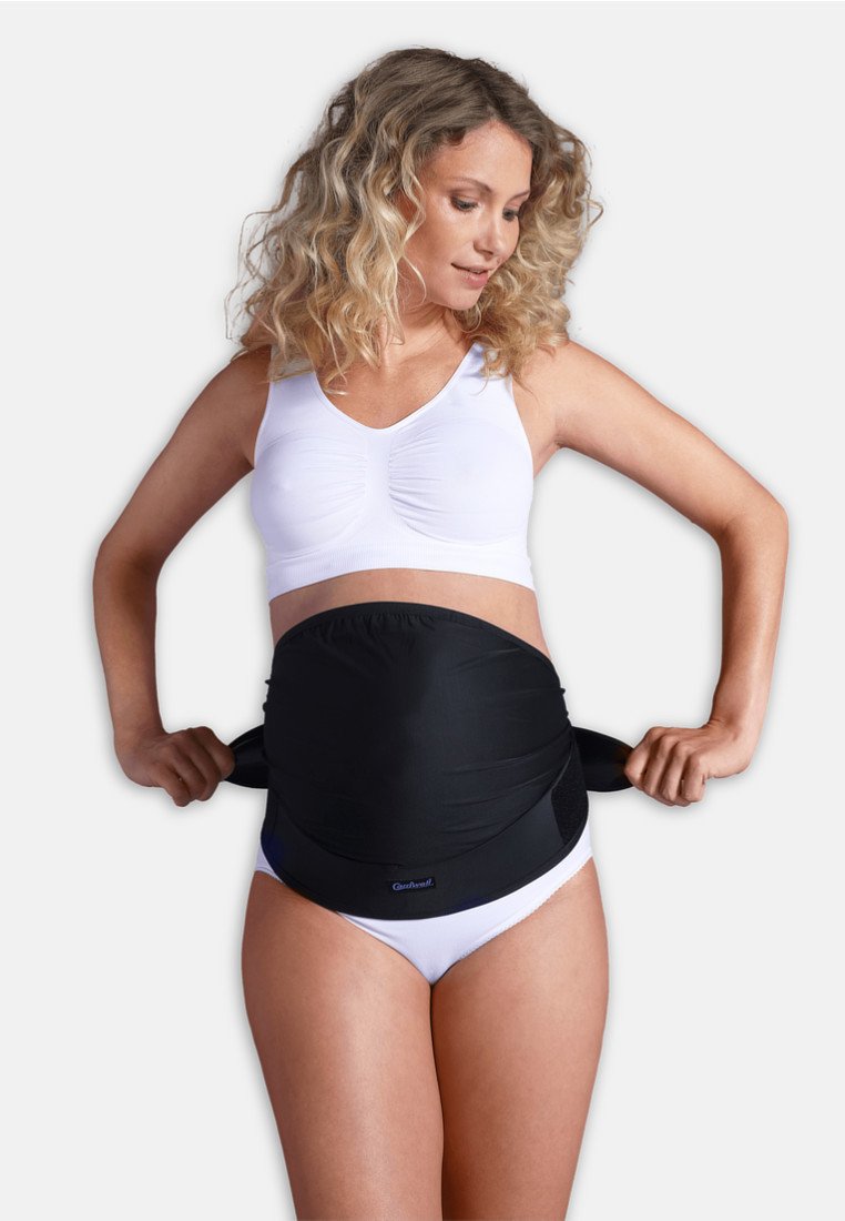 Mustavyö abdominal tukivyö säädettävillä hihnoilla, joka on puetun valkoisen paidan ja alusvaatteiden päälle. Sujuva pinta, joustava materiaali joustavuuden takaamiseksi.