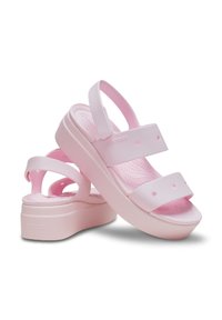 Pink platform sandals made of soft plastic with two wide straps, open toe, and circular cutouts, designed for comfort and breathability.