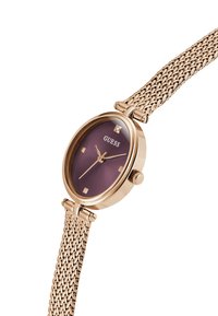 Montre en or rose avec un cadran violet, dotée de marqueurs d'heure carrés et d'un diamant à trois heures, complétée par un bracelet en métal tissé.