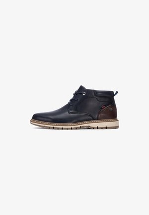 Botas de cuero hasta el tobillo en negro con un acento marrón, puntera redonda, diseño con cordones y suela de goma beige con textura.
