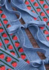 Jemná modrá pletenina so vzormi jahôd v radoch a prepletenými pletenými viazaniami na štruktúrovanej tkanine.
