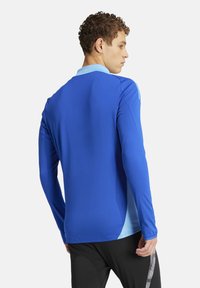 Lang mouw atletisch shirt in levendig blauw met lichte blauwe kraagaccenten, met een gladde textuur en een getailleerd ontwerp.