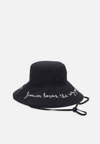 Fekete pamut napernyő sapka, széles karimával, feh�ér hímzett szöveggel, amely így szól: "fiorucci loves the way you". Állítható állszíj tartozik hozzá.