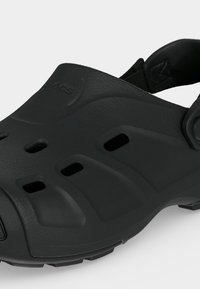 Μαύρο παπούτσι τύπου κλογκ με οπές αερισμού, επενδεδυμένο λουράκι στη φτέρνα και υφή στην σόλα για πρόσφυση και άνεση.