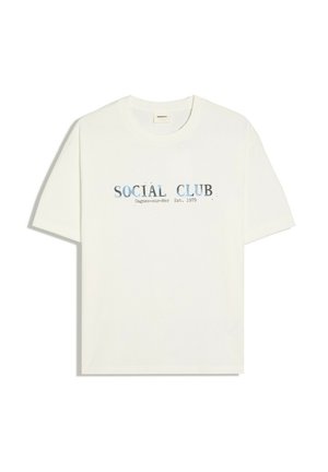 Biała koszulka z krótkim rękawem, okrągłym dekoltem i niebieskim napisem "SOCIAL CLUB Cagnes-sur-Mer Est. 1979" nadrukowanym na środku przodu.