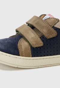 Blå ruskinnssneakers med brune skinnakenter, utstyrt med to borrelåser, perforerte detaljer og en teksturert kremfarget gummisåle.