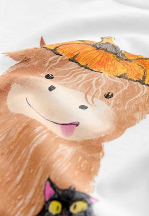 Biała tkanina z kolorową ilustracją uśmiechającego się bydła highland, które nosi dynię, obok czarnej kotki z żółtymi oczami.
