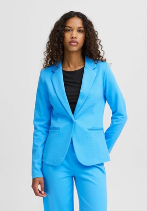 Helles blaues Blazer aus glattem Stoff, mit maßgeschneidertem Design, Reverskragen und zwei vorderen Taschen, kombiniert mit einem schwarzen Oberteil.