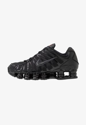Black athletic shoe with a mesh and synthetic upper, featuring a ribbed design, laces, and a chunky sole with visible cushioning units.