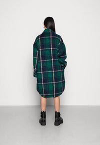 Grön och marinblå rutad oversize-skjorta i flanell, med rundad nederkant, långa ärmar, och matchad med svarta kraftiga stövlar.