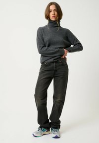 Grijze coltrui, zwarte recht gesneden jeans en multicoloured sportschoenen met mesh en rubberen details. Eenvoudige ontwerp elementen overal.