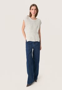 Top grigio chiaro a costine con maniche corte abbinato a jeans a vita alta e gamba larga di colore blu scuro e scarpe nere appuntite con dettagli a zebra.