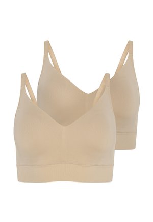 Helles beiges nahtloses Bralette und übergroße hellbraune Jacke, kombiniert mit weit geschnittenen blauen Jeans. Glatte Texturen und lässige Passform.