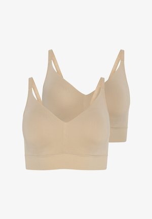 Beżowy bezszwowy biustonosz i oversize'owa jasnobrązowa kurtka zestawione z szerokimi niebieskimi dżinsami o szerokich nogawkach. Gładkie tekstury i luźny krój.