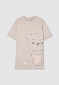 T-shirt beige a maniche corte con un'illustrazione di un grande orsetto che tiene un cuore rosa sul davanti.