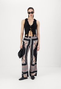 Fekete rövid felső fodros nyakkivágással, bőszárú nadrággal, virágmintával párosítva. Kiegészítők között napszemüveg és fekete táska található.