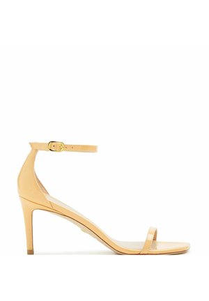 Beżowe sandały na wysokim obcasie z cienkim paskiem wokół kostki i otwartym noskiem. Wykonane z błyszczącego materiału o gładkiej teksturze i minimalnych detalach.