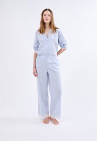 Juego de pijama a rayas azul y blanco que incluye una camisa de botones con cuello y pantalones holgados con encaje en el dobladillo. Tejido suave.