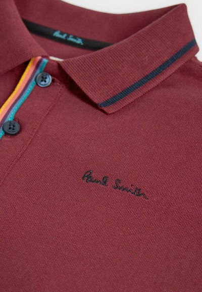 Bordo polo majica s teksturiranim materijalom, s kragnom, dva plava dugmeta i obojenim prugama duž zapleta i kragne.