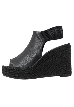 Sandales à talon en wedge noires avec une tige en cuir texturé, bout ouvert et bande élastique arborant le logo "RE" ; semelle intermédiaire en jute tissé et semelle extérieure noire.