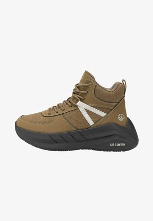 Brązowy sneaker typu high-top z czarną grubą podeszwą, białymi paskami po bokach, zaokrąglonym noskiem i logo Giesswein na obszarze pięty.
