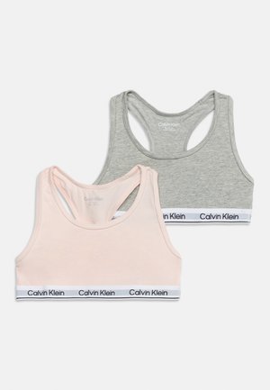Twee Calvin Klein racerback sportbeha's, één lichtroze en één grijs, elk met gebrande elastische banden aan de onderkant.