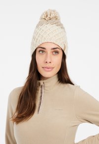 Beanie lavorato a maglia color crema con un motivo testurizzato e un pompon superiore. Un materiale morbido e accogliente, con un piccolo logo sul davanti.