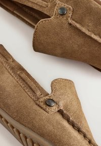 Nubuklederschuhe in Hellbraun mit glatter Oberfläche, mit einer Naht entlang der Kanten und einem schwarzen Logo-Button-Akzent an der Seite.