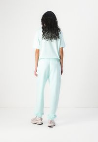Licht muntgroene top met korte mouwen en een losse pasvorm, gecombineerd met bijpassende joggers met een elastische tailleband en boorden; casual ontwerp en zachte textuur.
