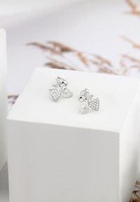 Silvriga studörhängen formade som stiliserade figurer, med en texturerad klänning prydd med klara kristaller. Lättviktig design med polerade detaljer.