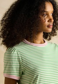 Roheline ja valge triibuline T-särk lühikeste pumbatud varrukatega ning roosa ribasilmadega kaelus. Pehme kangas ja vabalt istuv lõige.